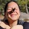 Close up of a smiling woman with a red admiral butterfly perched on her nose