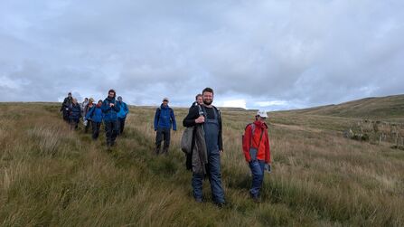 A group of course participants descending a moor under heavy clouds