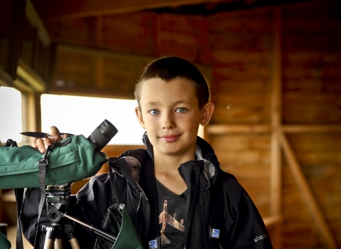 Ben in a bird hide with a telescope