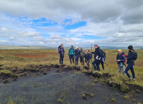 Peatland practitioner students receiving training next to a patch of bare peat in the Yorkshire Dales 
