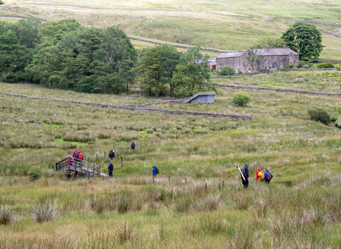 Wide shot of adults walking down peatland to return to Nethergill Farm